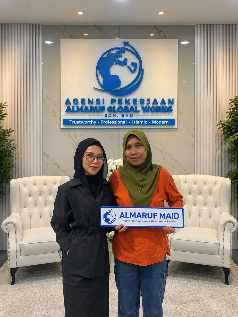 Two women at the Almaruf office, one holding an Almaruf Maid plate, in front of the agency's wall sign